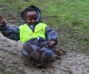 Child sliding in the mud