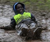Child happily sliding in the mud