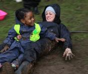 Child and adult smiling and playing in mud