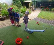 Children playing bean bap bop outside and walking a small plank