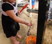 Child playing with water in the sandpit 